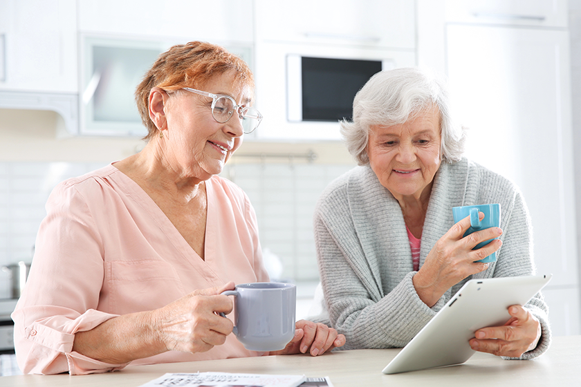 Elderly men using tablet PC at table in kitchen