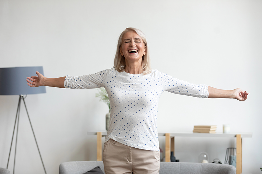 Happy mature woman standing with arms outstretched